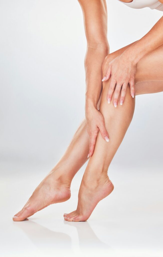 Woman, hands and legs in skincare for moisturizer, smooth or soft natural care against a white stud